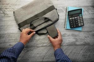 top view of young man putting office stationary in his bag photo