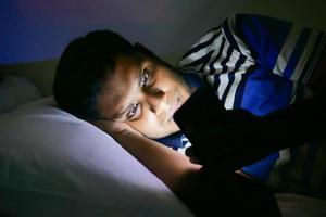 hombres jóvenes que usan teléfonos inteligentes en la cama por la noche foto