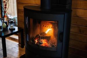 Burning wood in a modern black fireplace with a closed combustion chamber standing in the living room. photo