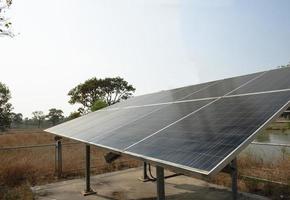 Los paneles solares producen electricidad que puede hacer funcionar una bomba de agua sumergida para el riego de agua en el campo agrícola foto