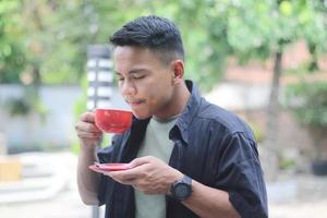 ASIAN YOUNG MAN DRINKING COFFEE IN THE MORNING photo