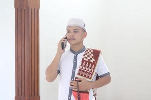 Young asian muslim praying in the mosque and calling her friend photo