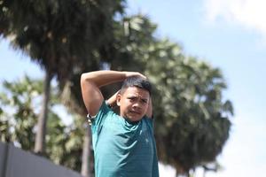 Young asian boy warming up for jogging in the morning photo