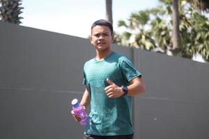 Young asian boy warming up for jogging in the morning and drinking mineral water photo