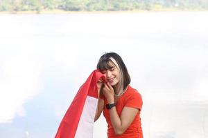 beautiful young asian woman carrying the indonesian flag with a cheerful face photo