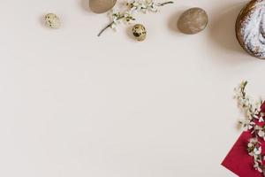 The Easter cake is decorated with powdered sugar, painted eggs on a beige background with a copy space. The eggs were colored beige with a decoction of nettle. Flat bed, top view photo