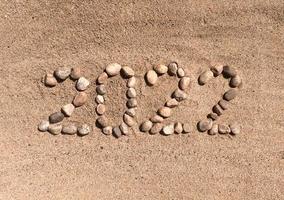 The numbers 2022 are written and lined with stones in the sand. Place for your text. Your text here. photo