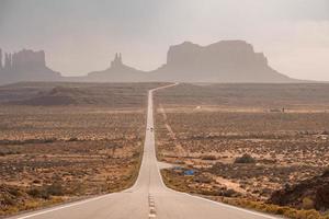 Road leading towards geological features in Monument Valley during summer photo