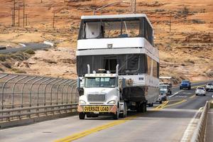 White Semi Truck With Oversize Load Sign Transporting Large Digger photo