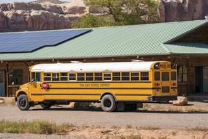 School Bus Parked By Building With Solar Panels On Roof photo