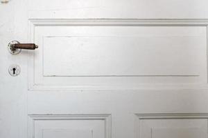 Closed old wooden white door with doorknob and keyhole, indoors. Copy space. photo