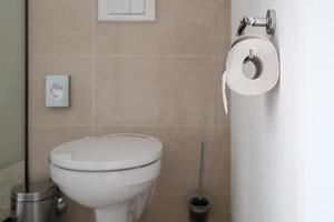 Roll of toilet paper on the holder, against the background of the toilet bowl in a modern bathroom. photo