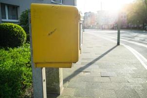 Yellow mailbox for letters on the street of a provincial town, in the sunlight. photo