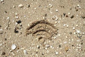 WiFi sign is drawn in the sand, on the seashore, on a summer day. Top view. photo