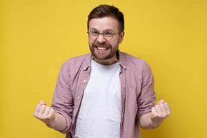 Man is pleased with the long-awaited victory, he grits his teeth and holds his fists. Yellow background. photo