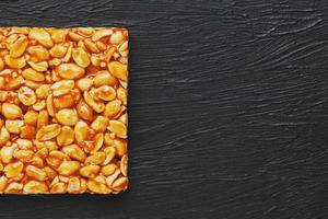 Golden boletus kozinaki from roasted peanut beans energy bars. Black textural background, top view photo