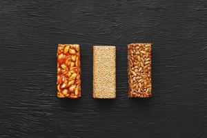 Healthy snacks. Fitness diet food. Grain bar with peanuts, sesame and seeds on a cutting board on a dark table, energy bars photo