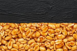 Golden boletus kozinaki from roasted peanut beans energy bars. Black textural background, top view photo