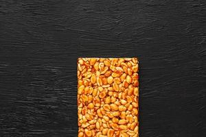 Golden boletus kozinaki from roasted peanut beans energy bars. Black textural background, top view photo