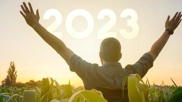 un joven feliz y satisfecho extiende sus manos en el aire y disfruta de la puesta de sol dando la bienvenida al nuevo año 2023. concepto de éxito, futuro de dedicación y establecimiento de objetivos foto