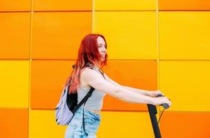 Young bright woman smiles and rides an electric scooter in the summer in city photo