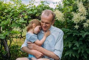 una niña abraza a su abuelo en un paseo al aire libre en verano. foto