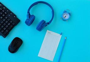 Flat lay home office desk. Workspace with laptop, headphones, pencil and a piece of paper for notes Expenses on blue background. Top view feminine background. photo