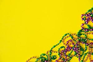 Mardi Gras concept. Multicolored beads on yellow background. Festive carnival symbols. photo