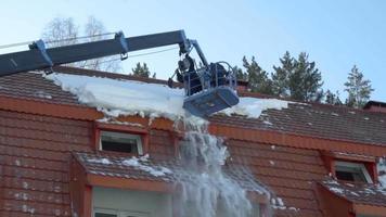 trabajador en camión elevador quitando nieve del techo del edificio, cámara lenta video