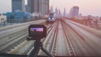 Camera on tripod film time-lapse in Dubai metro front seats. Scenic panorama of city skyline shooting video for social media.Commercial shooting license in famous landmarks concept photo