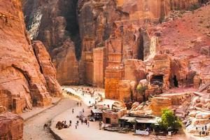 Tourist walk by caves of tombs in ancient city of Petra, Jordan. It is know as the Loculi. Petra has led to its designation as UNESCO World Heritage Site. photo