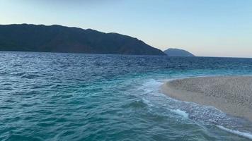 antenn exotisk ö strand hav vatten tidvatten se. klar turkos hav yta kustlinje djup trä video