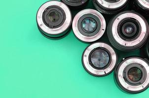 Several photographic lenses lie on a bright turquoise background. Copy space photo