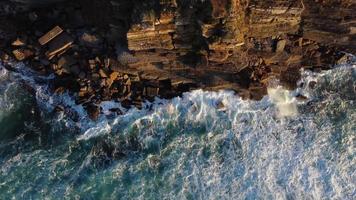 vista aérea de drones de las olas del océano chocando contra las rocas de un acantilado durante la puesta de sol. viajes y vacaciones. momentos relajantes. meditación y sensación de calma. video