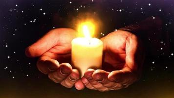 Hands holding white candle lit in the universe to celebrate christmas night. Fantasy theme video