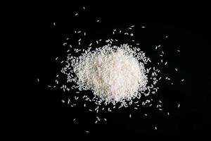 Pile of uncooked white rice on black background. Natural organic vegan food. photo