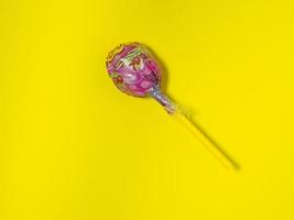 lollipop on a yellow background. Caramel on a stick. Not healthy food. photo