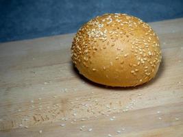 Bun with sesame seeds. Bakery products. Table in the bakery. White bun on a cutting board. Products made from wheat flour of the highest grade. photo