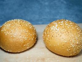 Bun with sesame seeds.  Table in the bakery. White bun on a cutting board. Products made from wheat flour of the highest grade. photo
