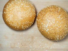 Bun with sesame seeds. Bakery products. Table in the bakery. White bun on a cutting board. photo