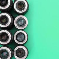 Several photographic lenses lie on a bright turquoise background. Copy space photo