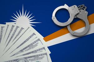 Marshall Islands flag with handcuffs and a bundle of dollars. The concept of illegal banking operations in US currency photo