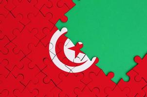 Tunisia flag is depicted on a completed jigsaw puzzle with free green copy space on the right side photo