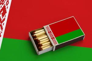 Belarus flag is shown in an open matchbox, which is filled with matches and lies on a large flag photo