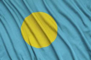 Palau flag is depicted on a sports cloth fabric with many folds. Sport team banner photo