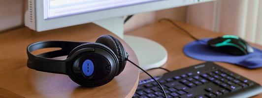 Big black headphones lie on the wooden desktop of the sound designer photo