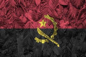 bandera de angola representada en muchas hojas de palmeras monstera. telón de fondo de moda foto