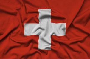 Switzerland flag is depicted on a sports cloth fabric with many folds. Sport team banner photo