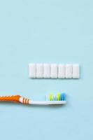 Toothbrush and chewing gums lie on a pastel blue background. Top view, flat lay. Minimal concept photo