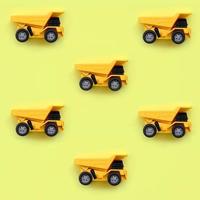 Many small yellow toy trucks on texture background of fashion pastel yellow color paper in minimal concept photo